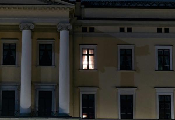 Une lumière est visible à une fenêtre du Palais royal alors que des personnes se rassemblent pour une veillée nocturne en l'honneur du roi Harald V de Norvège, sur la place du Palais à Oslo, tôt le 28 août 2026.