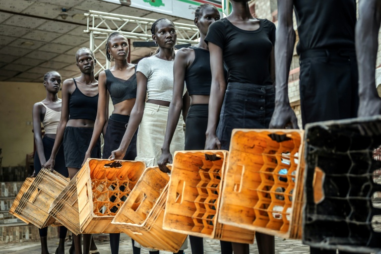Des jeunes mannequins de l'agence Jubalicious tiennent des casiers à bouteilles lors d'une séance de formation pour apprendre à défiler, le 19 février 2026 à Juba, au Soudan du Sud
