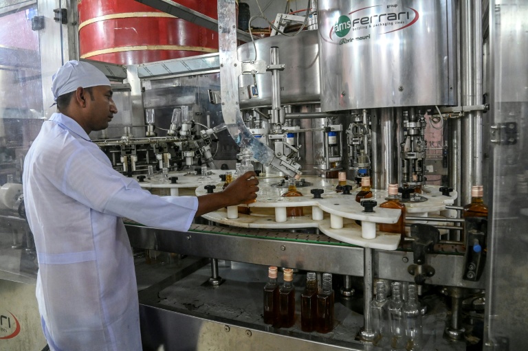 Un employé de la distillerie Carew and Co. contrôle une ligne d'embouteillage, à Darsana, le 23 octobre 2025 dans le sud-ouest du Bangladesh