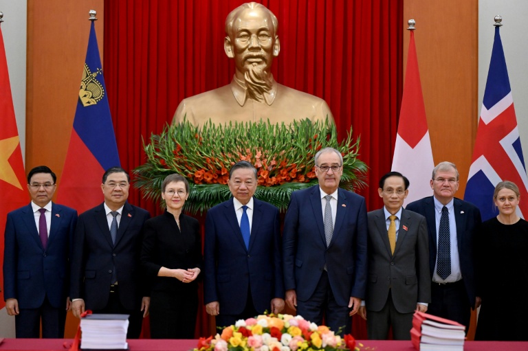 Le président du Vietnam, To Lam (c), la Première ministre du Liechtenstein, Brigitte Haas (3e g), et le président de la Suisse, Guy Parmelin (3e d), aux côtés de délégués lors de la cérémonie de signature de l'accord de libre-échange entre le Vietnam et l'AELE, le 18 octobre 2026 à Hanoï