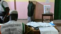 Une personne vote lors des élections législatives en Côte d'Ivoire, sous la surveillance d"un membre de la commission électorale indépendante, à  Abidjan le 27 décembre 2025