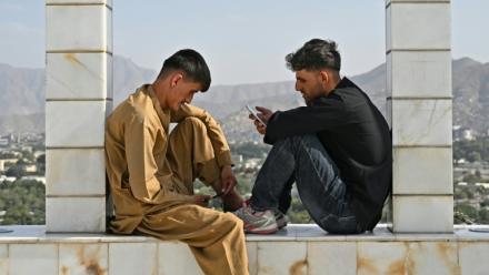 Des jeunes Afghans consultent leurs smartphones, sur la colline de Wazir Akbar Khan, à Kaboul, le 10 août 2026