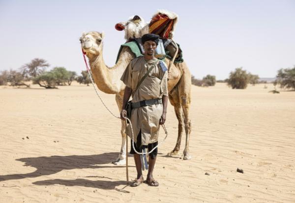 Sidnq, un membre de l'unité du Groupement nomade de la Garde nationale mauritanienne, pose pour un portrait à côté de son dromadaire dans la région de Hodh Ech Chargui (Mauritanie), le 7 avril 2025