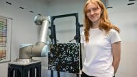 Audrey-Ève Goulet, artiste peintre, pose à côté d'un robot d'Acrylic Robotics qui reproduit une de ses oeuvres, le 12 août 2025 à Montréal