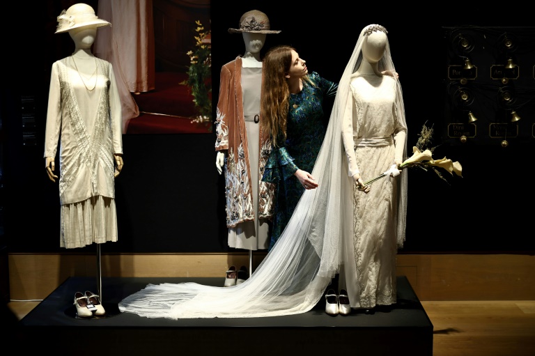 Une employée de la maison de vente aux enchères regarde une robe de mariée appartenant au personnage de Lady Mary de la série britannique Downton Abbey lors d'une avant-première presse pour une exposition d'accessoires, de costumes et d'autres articles de la franchise avant leur mise aux enchères, le 8 août 2025 à Londres