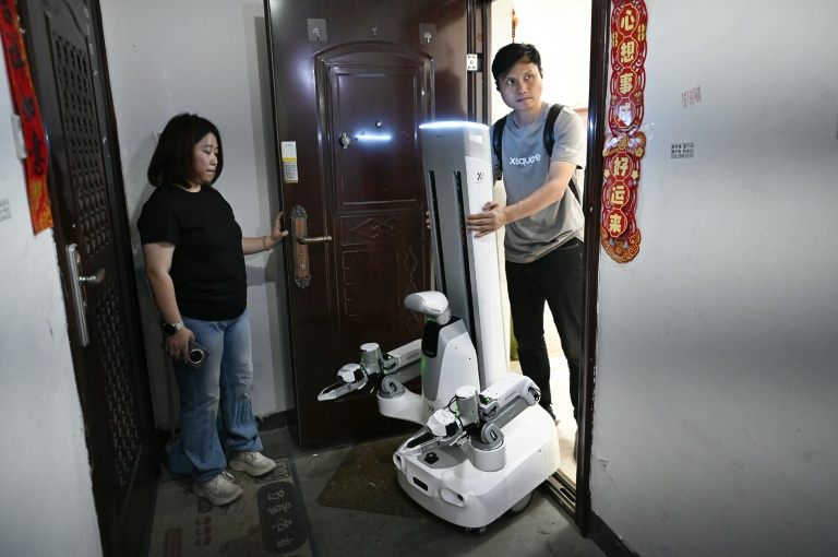 Un ingénieur de X Square emmène un robot après qu'il a effectué des tâches ménagères au domicile d'une cliente , le 21 mai 2026 à Pékin, en Chine