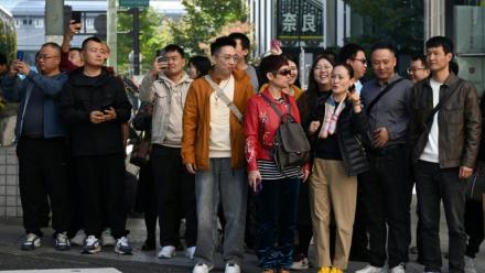 Un groupe de touristes chinois attend pour traverser une rue dans le quartier commerçant de Ginza, à Tokyo, le 16 novembre 2025
