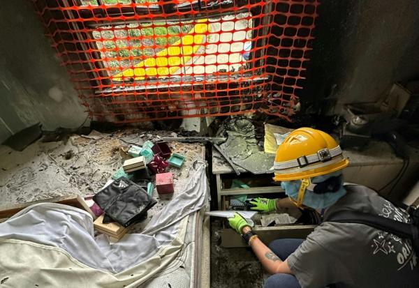 Sur cette photo prise et transmise le 23 avril 2026 par Bowie Chan, un habitant de Wang Fuk Court, son épouse Annie Tse fouille les tiroirs d'un meuble de leur appartement endommagé par l'incendie de novembre, à Hong Kong