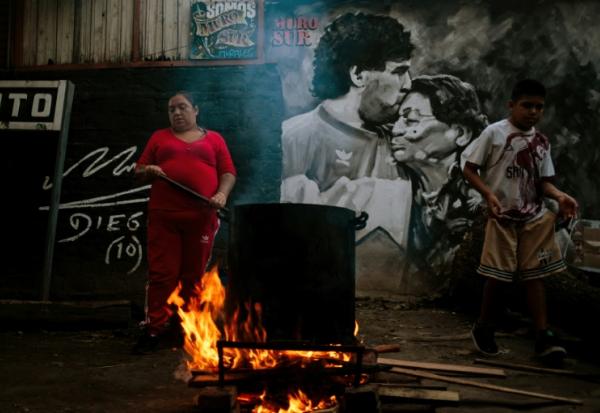 La cuisinière Maria Torres prépare un ragoût pour ses voisins dans le besoin, dans la cour de la maison d'enfance de la star du football Diego Maradona, aujourd'hui transformée en soupe populaire, à Villa Fiorito, le 9 avril 2026 dans la province de Buenos Aires, en Argentine