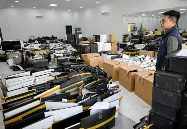 Un policier à côté de matériel saisi dans des centres d’opérations de cyberarnaques, au commissariat de la police municipale de Phnom Penh, le 11 mars 2026 au Cambodge