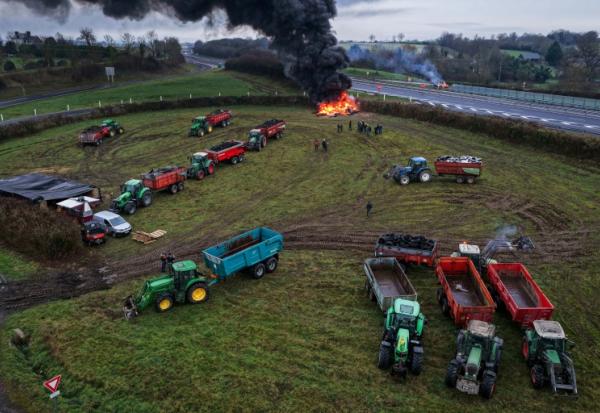 Des agriculteurs allument un feu alors qu'ils participent, avec leurs véhicules, à un blocage d'autoroute, à Poilley, dans l'ouest de la France, le 5 janvier 2026