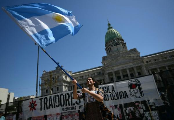 Un manifestant brandit le drapeau national argentin lors d'une manifestation devant le Parlement où est examinée la réforme du travail du président Javier Milei, à Buenos Aires, le 27 février 2026