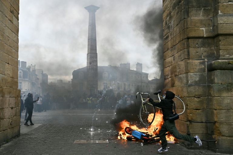 Un manifestant soulève un vélo à côté d’un feu lors d’une manifestation contre la vie chère, place de la Victoire à Bordeaux, en Gironde