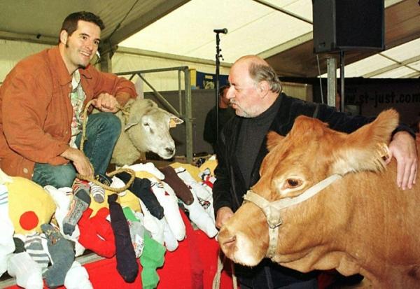 Philippe Soulas (D) tient la vache qu'il s'est vu offrir par le cou, le 09 octobre 1999, après avoir remporté le prix de l'humour vache au 18e Salon International de dessin de presse et d'humour de Saint-Just-Le-Martel (Haute-Vienne). Ivan Sigg, proclamé vainqueur du prix de l'humour tendre a reçu un agneau du Limousin.     