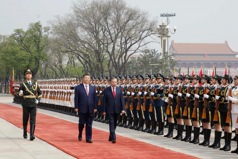 Photo prise et diffusée par l'Agence de presse vietnamienne (VNA), le 15 avril 2026, montrant le président chinois Xi Jinping (c) et le président vietnamien To Lam (d) inspectant la garde d'honneur au Palais de l'Assemblée du Peuple à Pékin