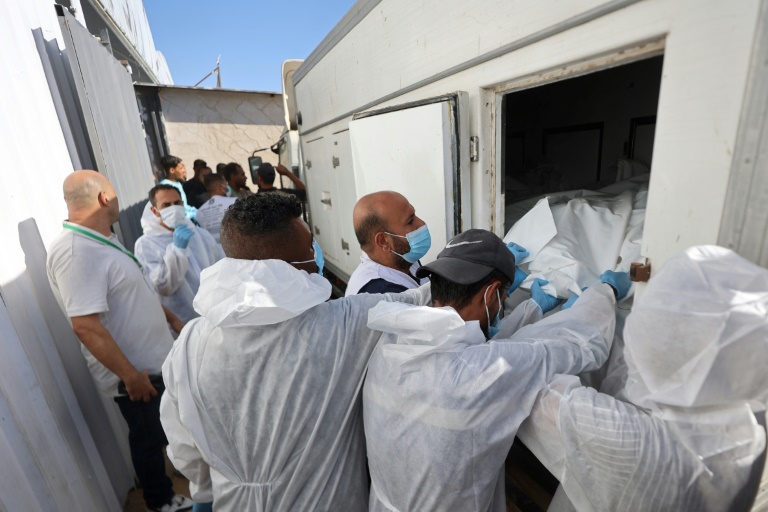 Des employés de la morgue déchargent les corps de Palestiniens qui étaient détenus par Israël, après leur transport par des véhicules du Croissant-Rouge et des camions frigorifiques, à l’hôpital Nasser de Khan Younès, dans le sud de la bande de Gaza, le 15 octobre 2025