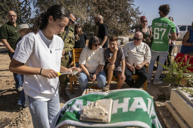 Des habitants du kibboutz de Kfar Aza dans le sud d'Israël, se recueillent devant une tombe lors d'une cérémonie en hommage aux personnes tuées lors de l'attaque du Hamas le 7 octobre 2023, le 16 octobre 2025