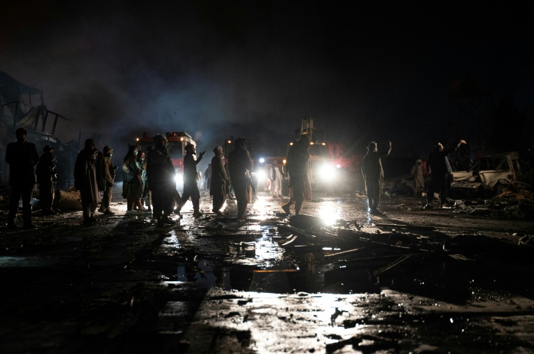 Des pompiers afghans et des agents de sécurité talibans travaillent sur le site d'un incendie après des frappes pakistanaises, le 16 mars 2026 à Kaboul