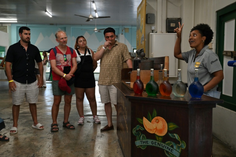 La guide Genesis Riley (D) explique à des touristes la production de liqueur curaçao dans la distillerie Willemstad, sur l'île néerlandaise de Curaçao, au large du Venezuela, le 9 avril 2026
