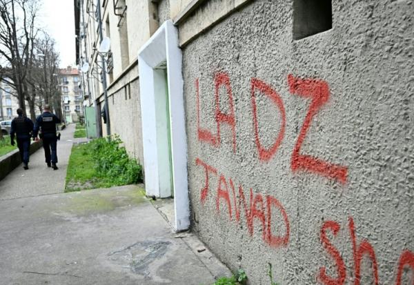 Des policiers patrouillent à proximité d'un mur avec un tag DZ désignant la DZ mafia à Avignon le 13 mars 2025