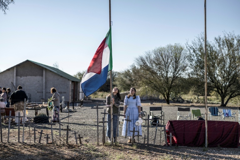 Une habitante d'Orania, Cara Tomlinson, hisse le drapeau de l'ancienne République sud-africaine au cimetière construit sur les lieux d'un camp de concentration de la guerre anglo-boer à Doornbult, près d'Orania, le 30 mai 2026.