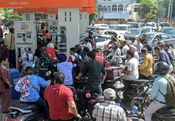 Des personnes se précipitent pour faire le plein de leur véhicule dans une station-service à Amritsar, le 27 mars 2026, en Inde