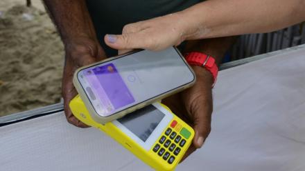 Une femme règle un achat sur la plage de Copacabana à l'aide du système de paiement instantané brésilien PIX, à Rio de Janeiro, le 9 juillet 2026 au Brésil