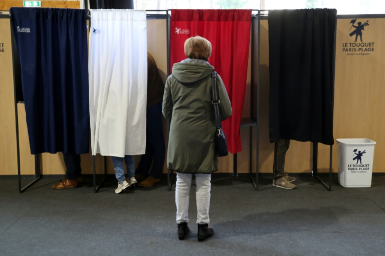 Une femme attend qu'un isoloir se libère pour voter au premier tour des élections municipales, le 15 mars 2026 au Touquet 