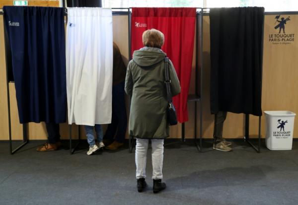 Une femme attend qu'un isoloir se libère pour voter au premier tour des élections municipales, le 15 mars 2026 au Touquet 