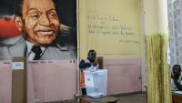 Un représentant de la commission électorale compte les votes de la présidentielle ivoirienne devant un tableau du premier président de Côte d'Ivoire, Félix Houphouët-Boigny, le 25 octobre 2025 à Abidjan