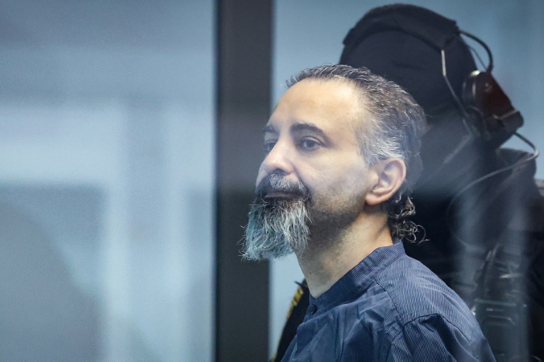 L'accusé saoudien Taleb Jawad al-Abdulmohsen (c) dans le box en verre pare-balle de la salle d'audience provisoire de Magdebourg, lors de son procès pour avoir foncé avec un SUV dans la foule d'un marché de Noël fin 2024, le 26 juin 2026 dans l'est de l'Allemagne