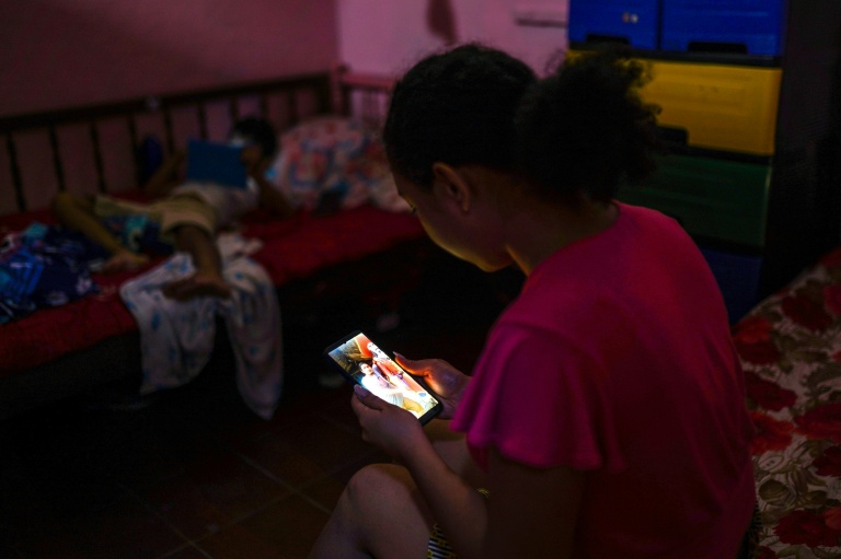 Carmen, 17 ans, regarde une photo de son père sur son téléphone, le 12 décembre 2025 à Zacatecoluca, au Salvador