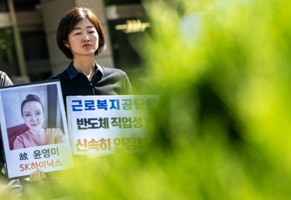 Militants et proches brandissent le portrait d'une ancienne employée de SK hynix, lors d'un rassemblement devant une antenne du Service sud-coréen d'indemnisation et de protection sociale des travailleurs, à Séoul, le 7 octobre 2026