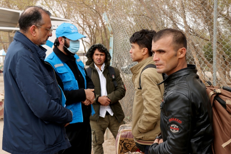 Arafat Jamal (g), représentant en Afghanistan du Haut-Commissariat de l'ONU pour les réfugiés (HCR), parle avec des ressortissants afghans à leur arrivée au point de passage frontalier d'Islam Qala, entre l'Afghanistan et l'Iran, dans la province d'Hérat, le 10 mars 2026