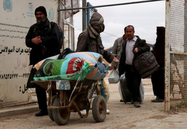Des Afghans, quittant l'Iran, reviennent dans leur pays au poste-frontière d'Islam Qala, dans la province de Hérat, le 10 mars 2026
