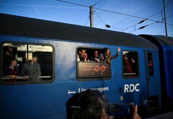 Des passagers saluent les journalistes depuis un wagon du premier train de nuit de la ligne Paris-Berlin gérée par la compagnie néerlando-belge European Sleeper, au départ de la Gare du Nord à Paris, le 26 mars 2026
