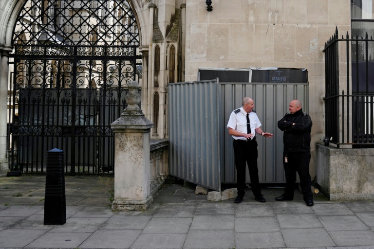 Des agents de sécurité montent la garde devant des palissades qui dissimulent la dernière oeuvre de Banksy montrant un juge frappant un manifestant avec son marteau, apparue le 8 septembre 2025 sur un mur de la Royal Court of Justice à Londres