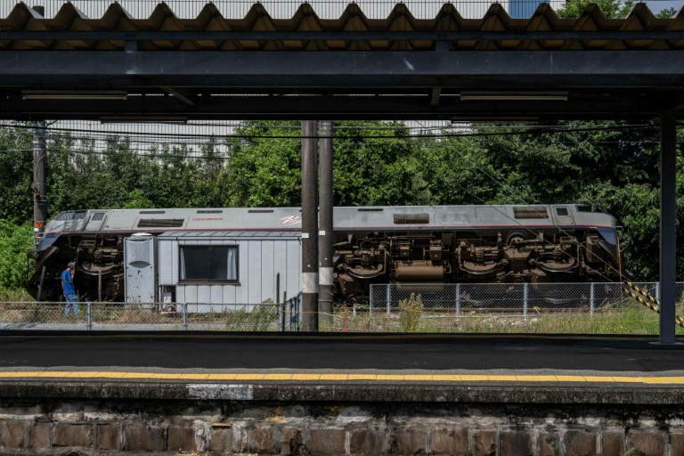 Un homme parle au téléphone à côté d’un train qui a déraillé et s’est renversé à Yatsushiro, dans la préfecture de Kumamoto, le 29 juillet 2026, après qu’un tremblement de terre a frappé le sud-ouest du Japon la veille