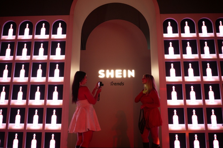 Des invités posent devant le logo Shein pendant le premier défilé italien de la plateforme, le 16 octobre à 2025 à Milan   
