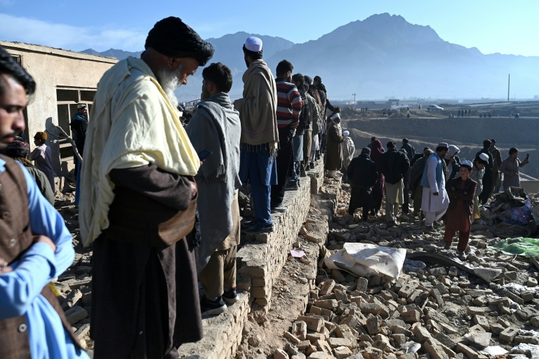 Des habitants rassemblés autour d'habitations endommagées après des bombardements, en périphérie de Kaboul, le 13 mars 2026 en Afghanistan
