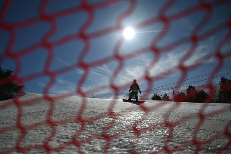 Un touriste fait du snowboard sur les pistes de la station de ski de Lianhuashan, en périphérie de Pékin, le 16 février 2026 en Chine