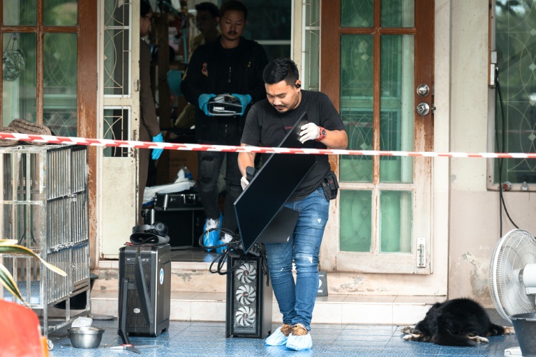 Un enquêteur emporte un ordinateur hors de la maison où un adolescent a tué ses grands-parents avant de perpétrer une fusillade dans une école au nord de Bangkok, la capitale de la Thaïlande (7 août 2026)