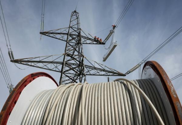 Des apprentis suivent une formation sur un pylône au centre de formation de National Grid à Eakring, dans le centre de l'Angleterre, le 28 avril 2025, perchés à 45 mètres de hauteur
