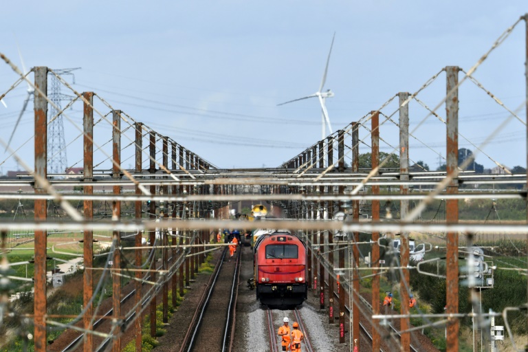 Des employés inspectent les voies autour d'un train-usine transportant des sections de rails et de traverses, lors de la rénovation de la ligne interurbaine POLT (Paris-Orléans-Limoges-Toulouse), près d'Artenay, le 16 septembre 2025 dans le Loiret