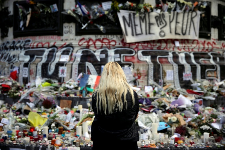 Une femme se recueille devant un mémorial improvisé composé de fleurs, de bougies et de messages, place de la République à Paris, le 17 novembre 2015, en hommage aux victimes des attentats du 13 novembre 2015