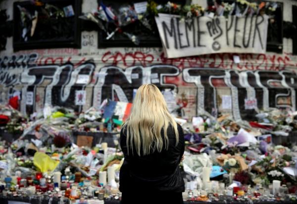 Une femme se recueille devant un mémorial improvisé composé de fleurs, de bougies et de messages, place de la République à Paris, le 17 novembre 2015, en hommage aux victimes des attentats du 13 novembre 2015