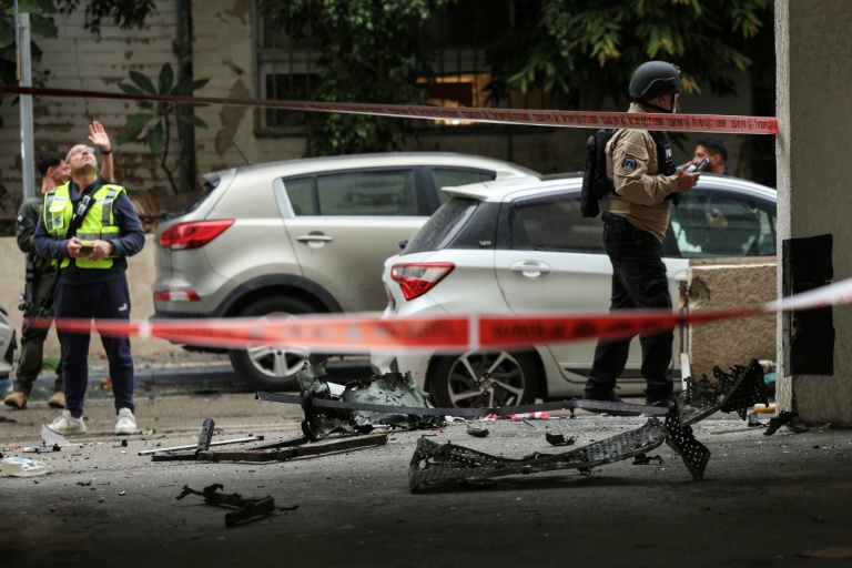 Des membres forces de sécurité israéliennes et des secouristes sur le site d'un impact dans un quartier résidentiel de Tel-Aviv après une frappe iranienne, le 1er avril 2026