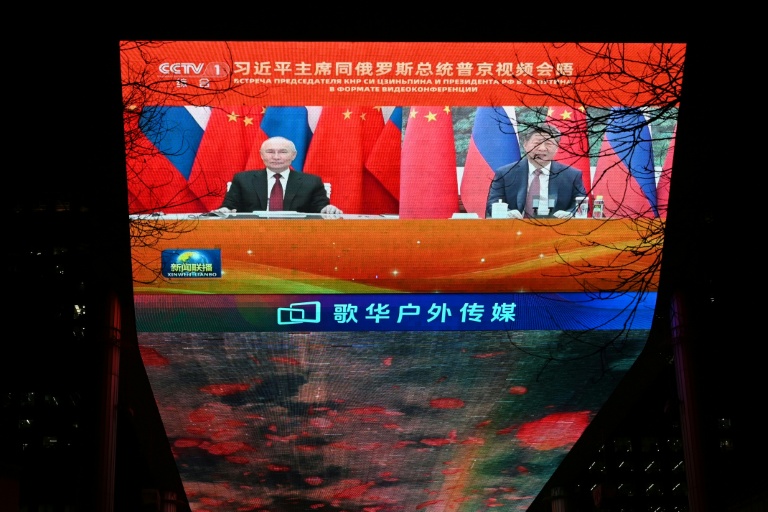 Le président russe Vladimir Poutine à gauche et le président chinois Xi Jinping à droite lors d'un entretien en visioconférence, retransmis sur un écran à Pékin le 4 février 2026