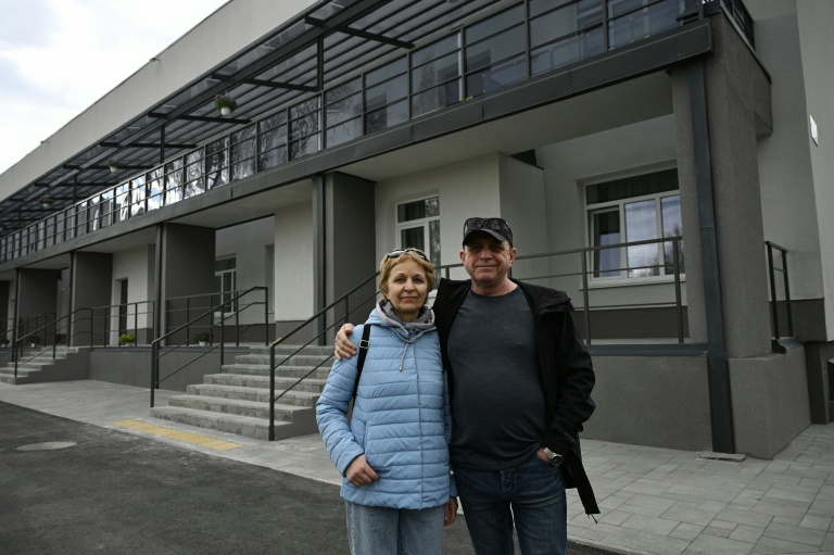 Maryna et son époux Volodymyr, déplacés par la guerre, posent devant un bâtiment rénové dans la ville de Slavoutytch dans le nord de l'Ukraine, le 25 avril 2026 