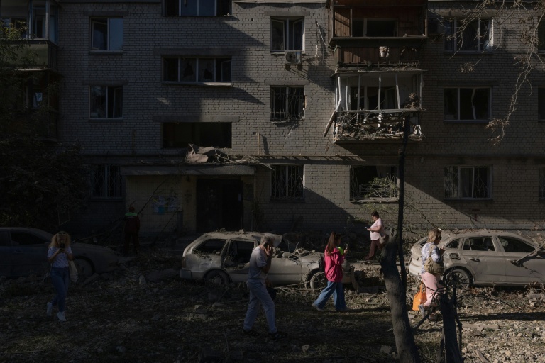 Des habitants passent devant un immeuble endommagé par une frappe aérienne russe à Kiev, le 20 août 2026 en Ukraine